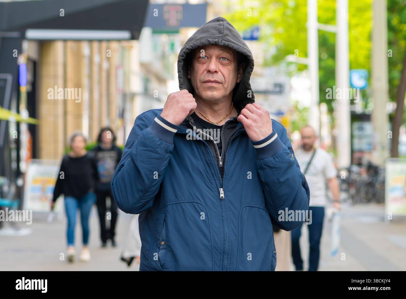 Un uomo incappucciato sullo sfondo del trambusto urbano è un abitante moderno della città Foto Stock