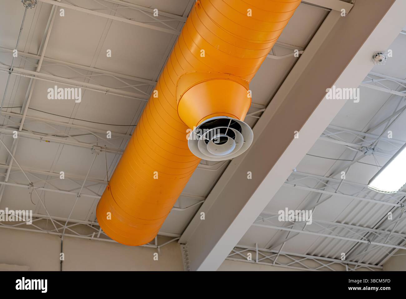 HVAC per interni, sistemi meccanici, condotto arancione, tubi di ventilazione, con diffusore bianco, appeso al soffitto di un grande spazio aperto. Foto Stock