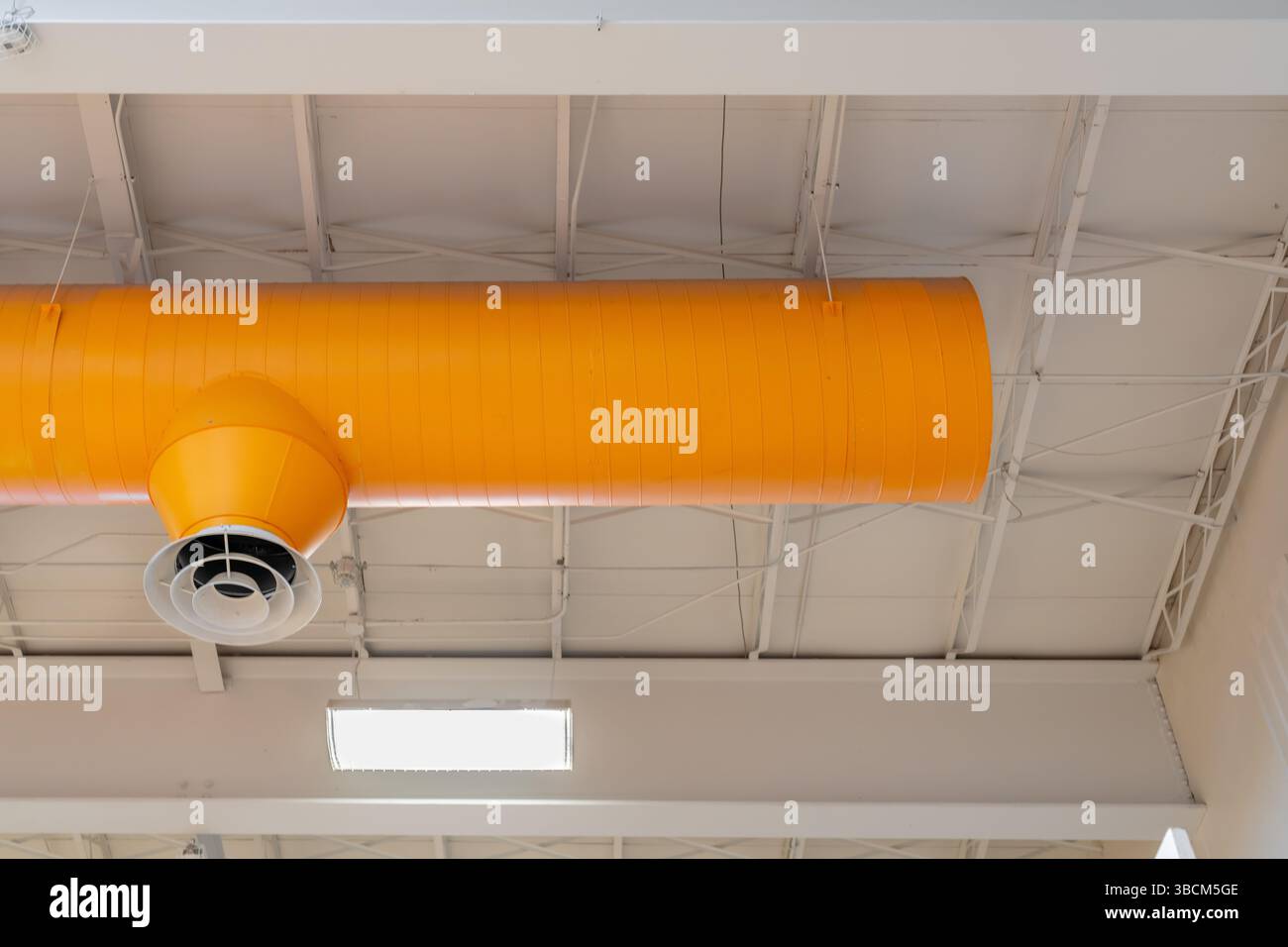 HVAC per interni, sistemi meccanici, condotto arancione, tubi di ventilazione, con diffusore bianco, appeso al soffitto di un grande spazio aperto. Foto Stock
