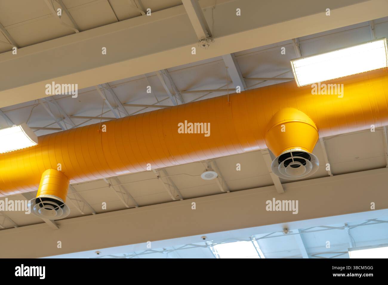 HVAC per interni, sistemi meccanici, condotto arancione, tubi di ventilazione, con diffusore bianco, appeso al soffitto di un grande spazio aperto. Foto Stock