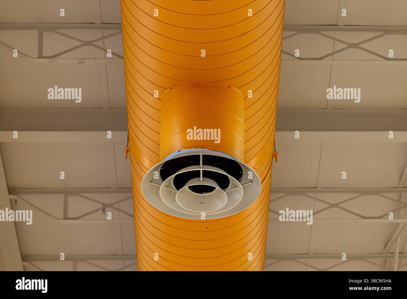HVAC per interni, sistemi meccanici, condotto arancione, tubi di ventilazione, con diffusore bianco, appeso al soffitto di un grande spazio aperto. Foto Stock
