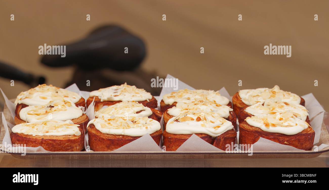 Un vassoio di rotoli dorati alla cannella ricoperti di cremosa glassa e cosparsi di noci, creando un'immagine invitante e appagante per dessert o panetteria Foto Stock