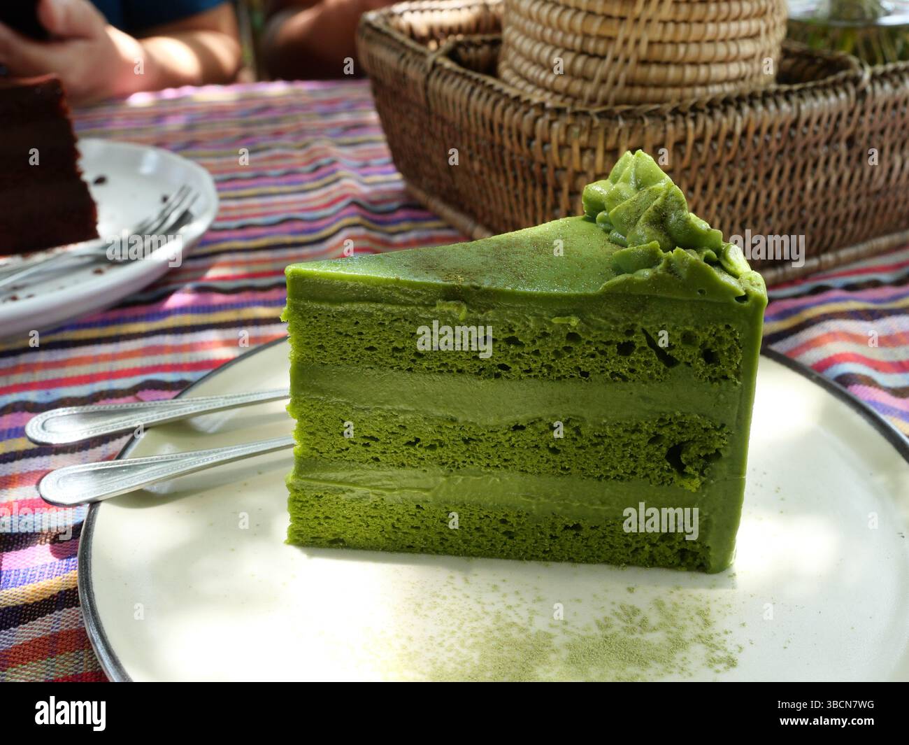 Tè triangolare matcha in piatto sul tavolo, panetteria ricoperta di panna verde Foto Stock