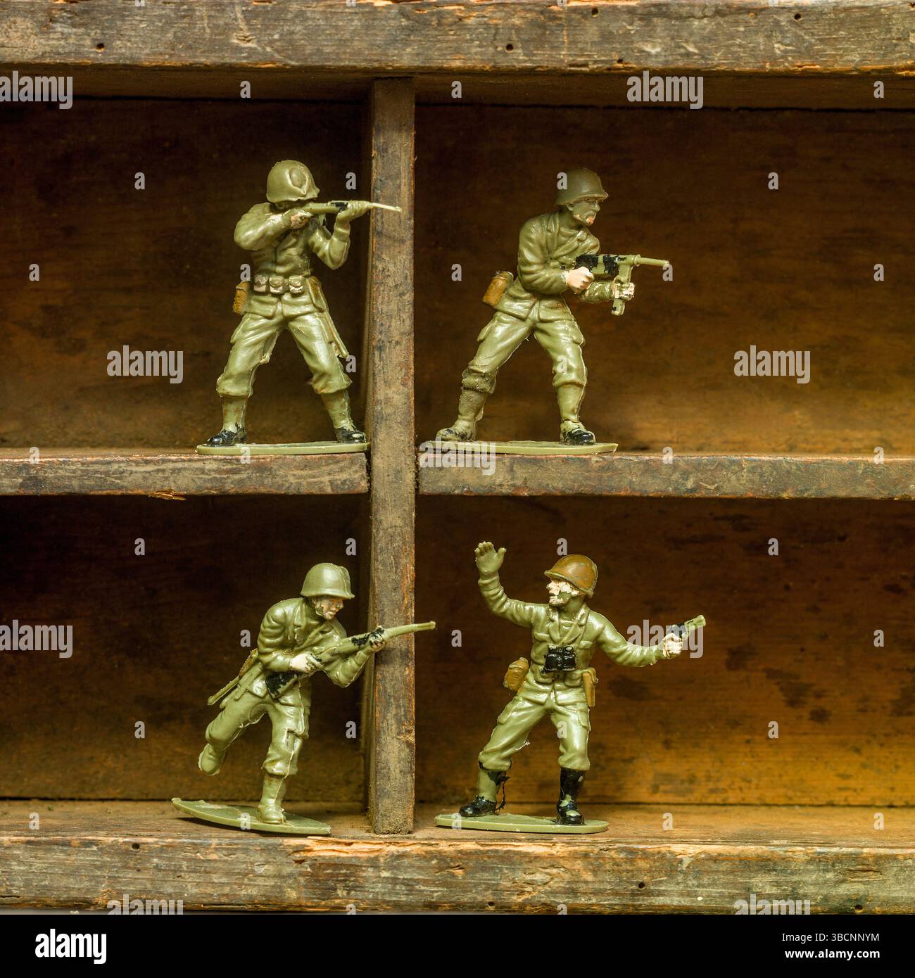 Un set di soldati giocattolo di plastica classici disposti su una mensola di legno, che mostra i soldati in varie pose d'azione con fucili e attrezzature Foto Stock