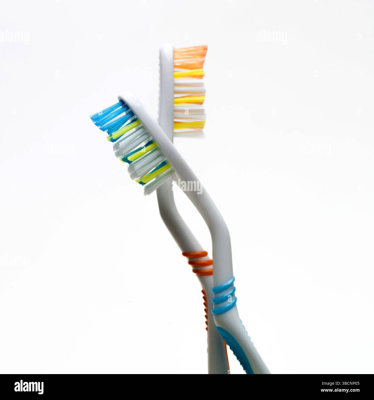L'immagine presenta due spazzolini intrecciati tra loro, evidenziando i colori vivaci delle setole e le forme ergonomiche uniche. Foto Stock
