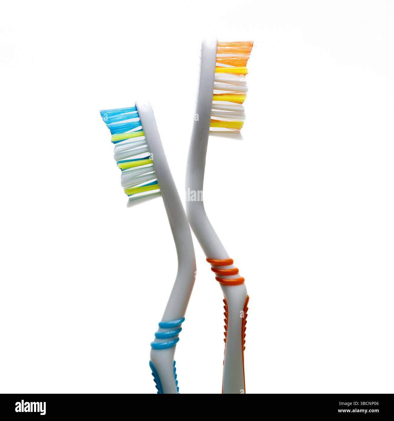 Due spazzolini dai colori vivaci si posizionano inclinati su uno sfondo semplice. Sottolineano l'importanza dell'igiene dentale e della cura orale quotidiana Foto Stock