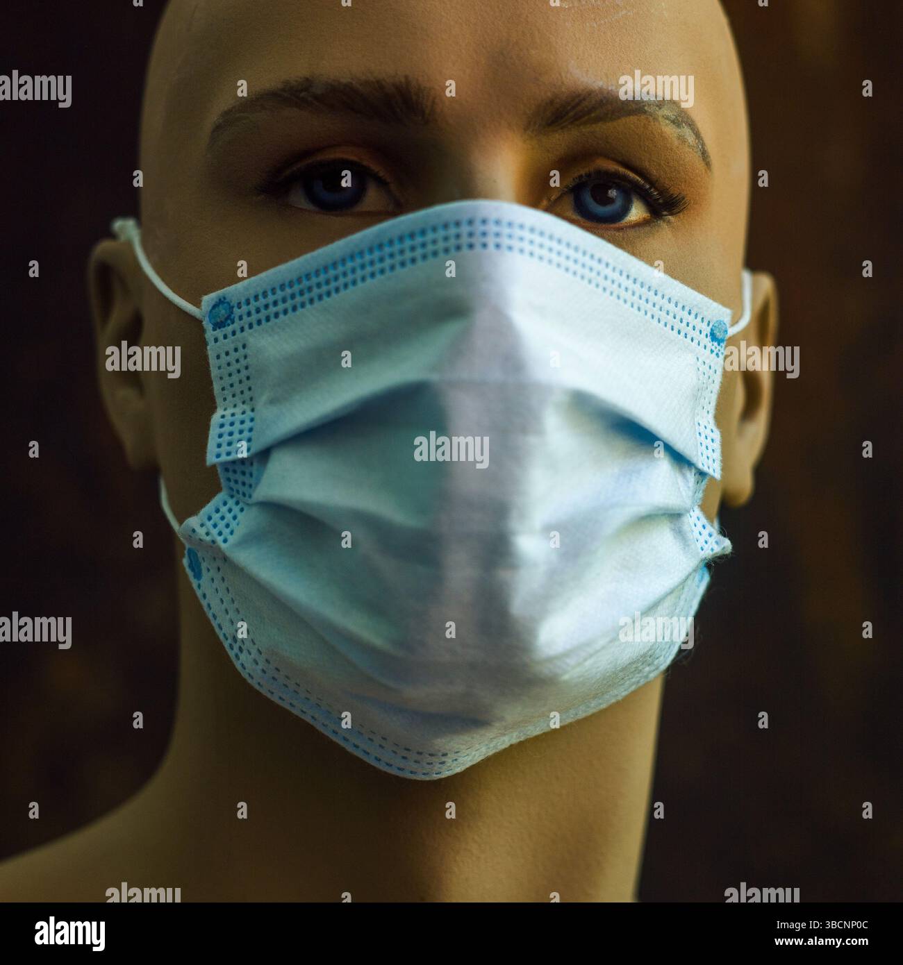 Un manichino mostra una maschera chirurgica azzurra, sottolineando il significato della sicurezza sanitaria durante le riunioni pubbliche. Foto Stock
