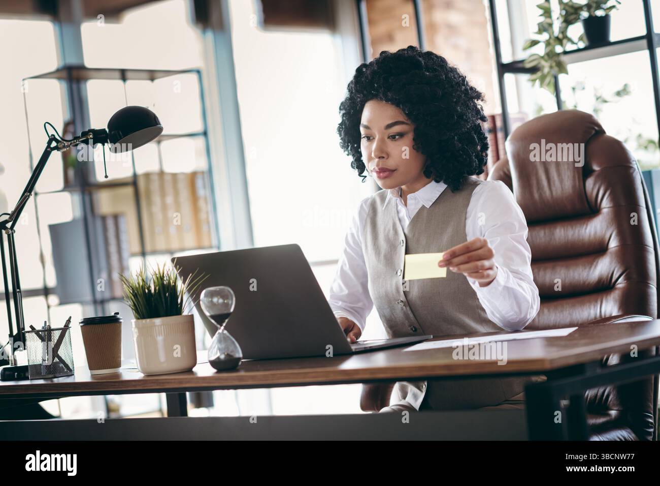Donna d'affari professionale che lavora in modo efficiente in un ufficio moderno, mentre esamina appunti e pianifica Foto Stock