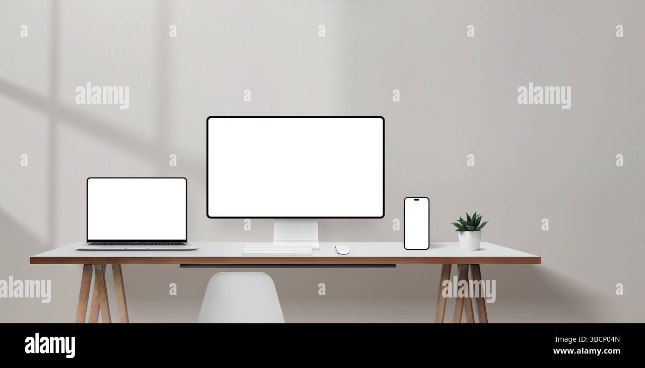 Scrivania da ufficio luminosa con laptop, monitor per computer e mockup per smartphone, spazio vuoto a parete per la copia promozionale Foto Stock