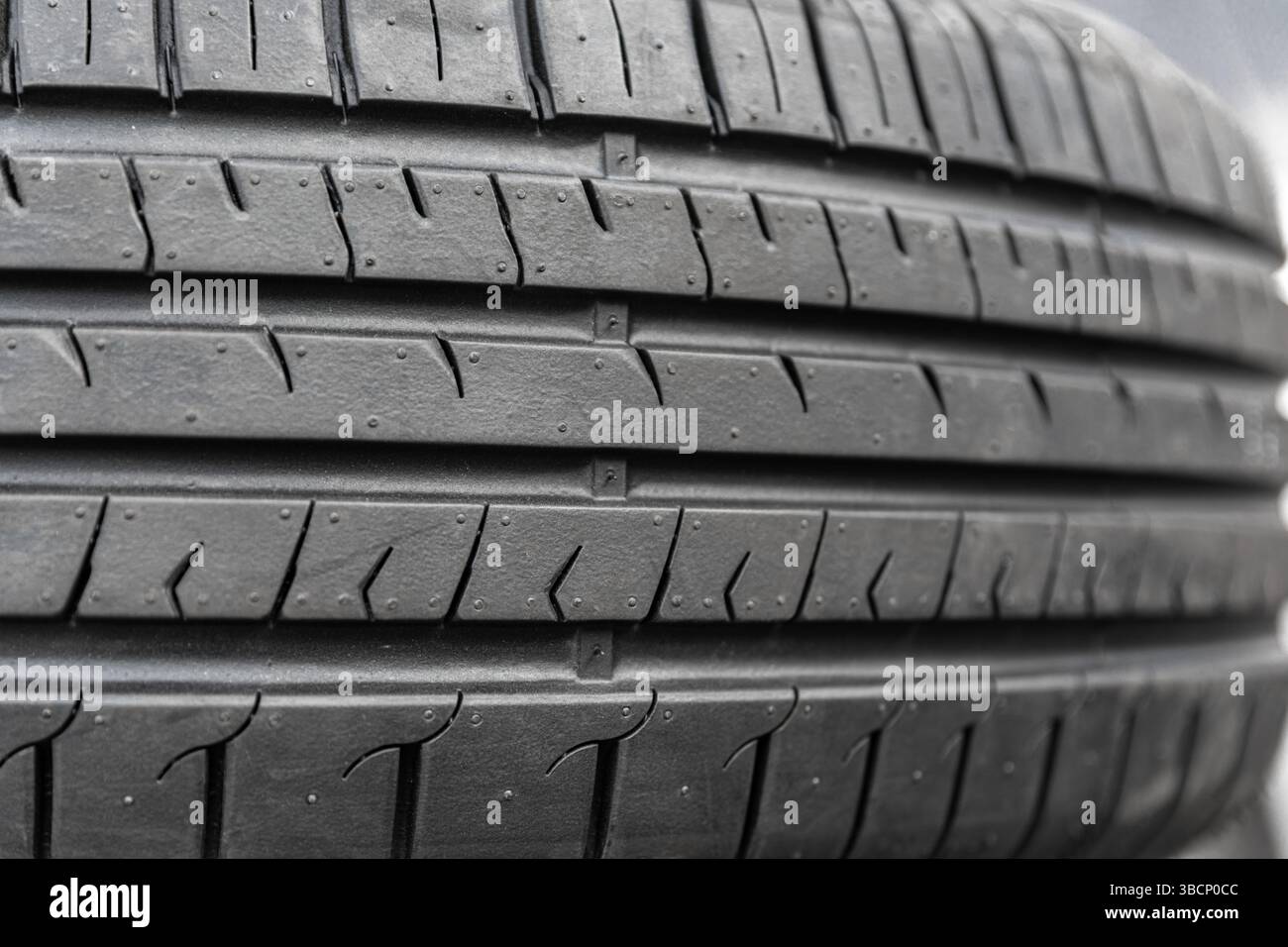 Foto macro di un battistrada nero pulito con scanalature simmetriche, ideale per temi legati al settore automobilistico e dei trasporti. Foto Stock