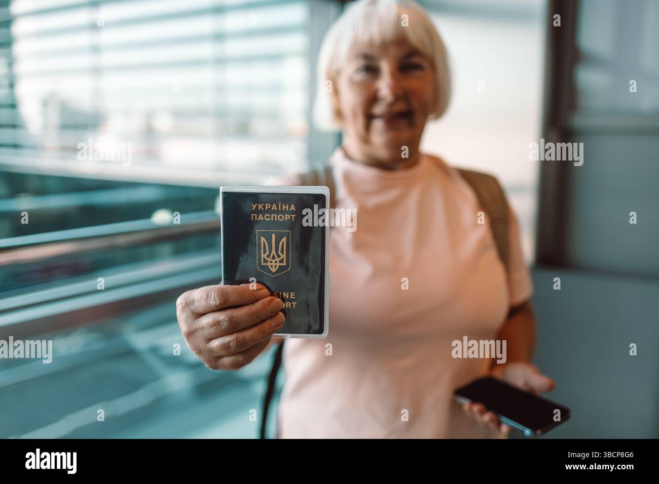 Donna anziana con passaporto e smartphone al check-in in aeroporto Foto Stock