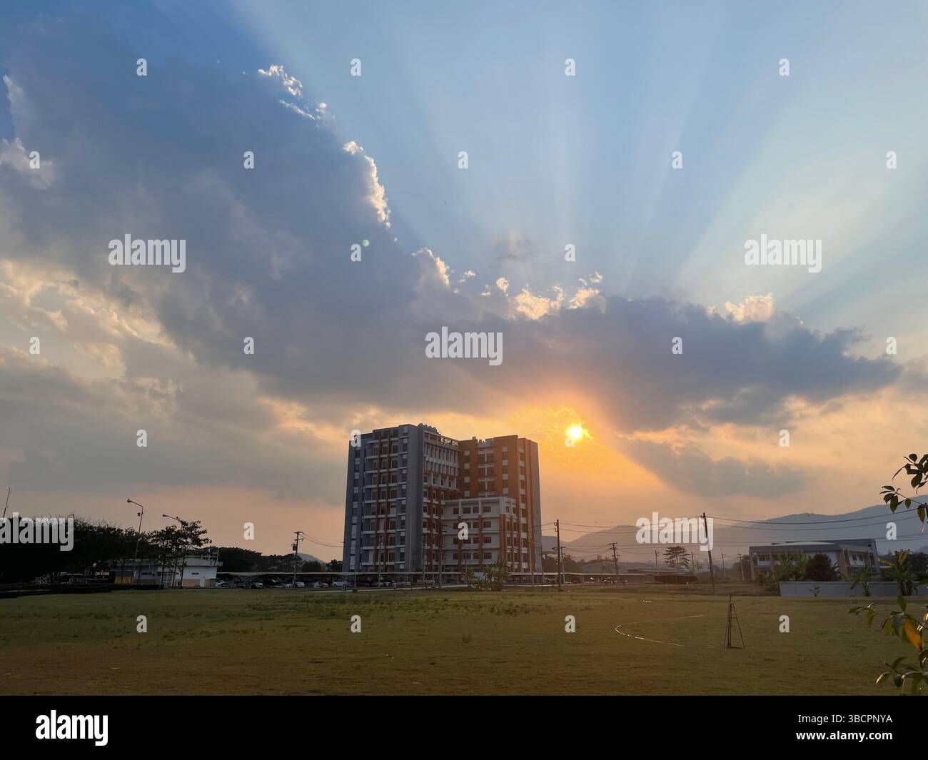 L'edificio MED-MFU si erge con orgoglio contro un tramonto dorato dove l'innovazione incontra la serenità in una fusione mozzafiato di architettura e bellezza naturale Foto Stock