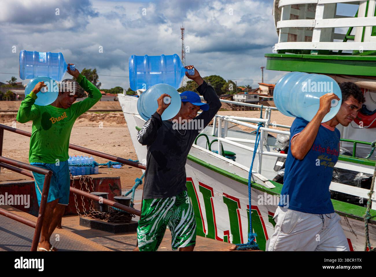 I lavoratori portuali caricano litri d'acqua potabile sulle tradizionali barche fluviali amazzoniche presso il porto di Santarém a Pará, Brasile. Foto Stock