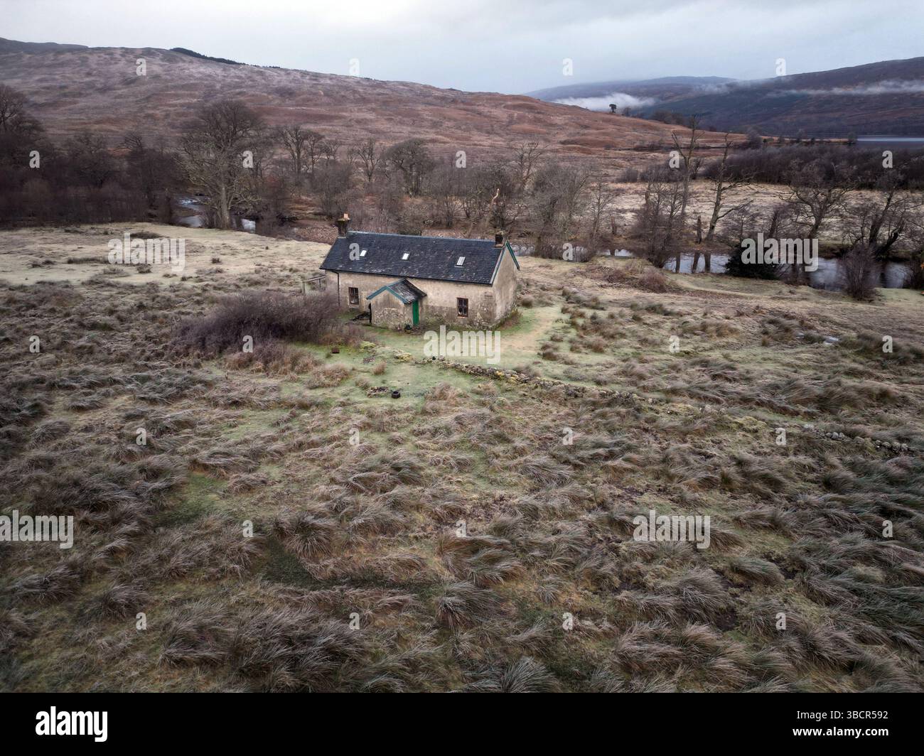 Vista aerea di Invermallie Bothy nelle remote Highlands scozzesi, un rifugio di montagna annidato accanto a un fiume tortuoso in un paesaggio selvaggio e ghiacciato Foto Stock
