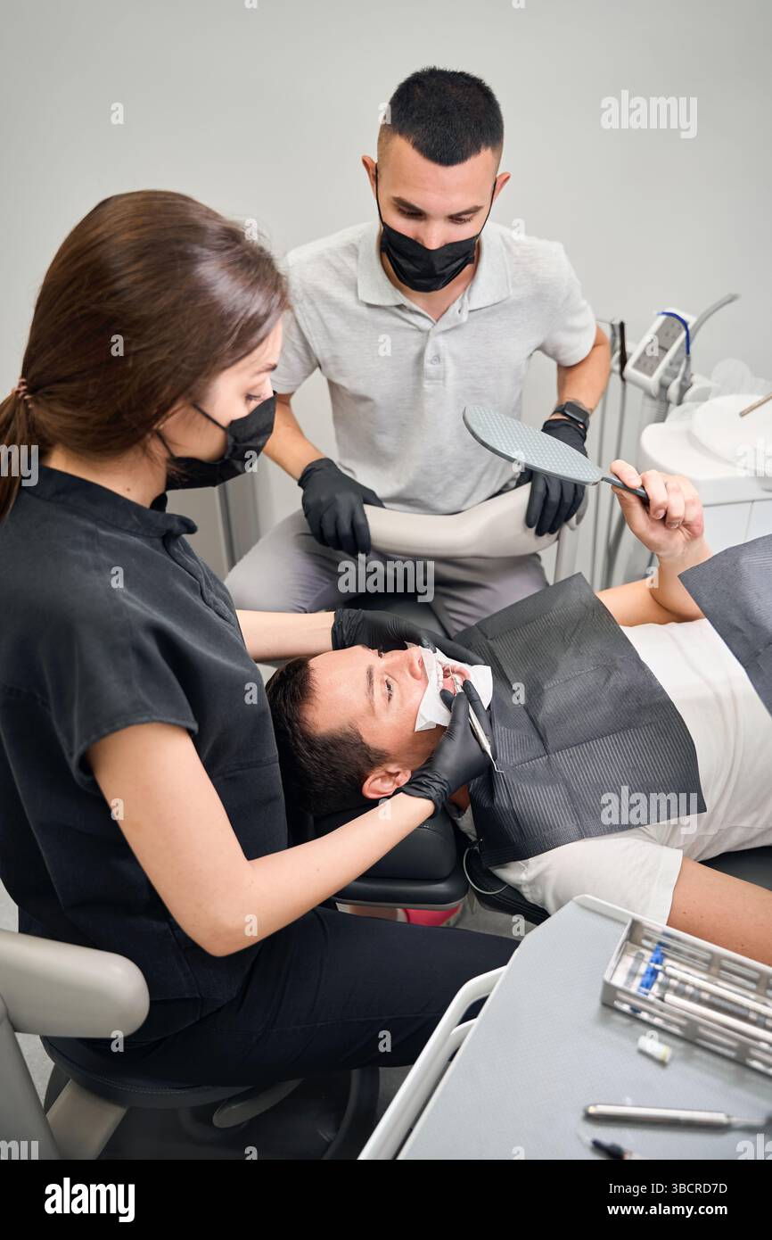 Lo Stomatologo mostra il dente problematico e spiega come trattarlo Foto Stock