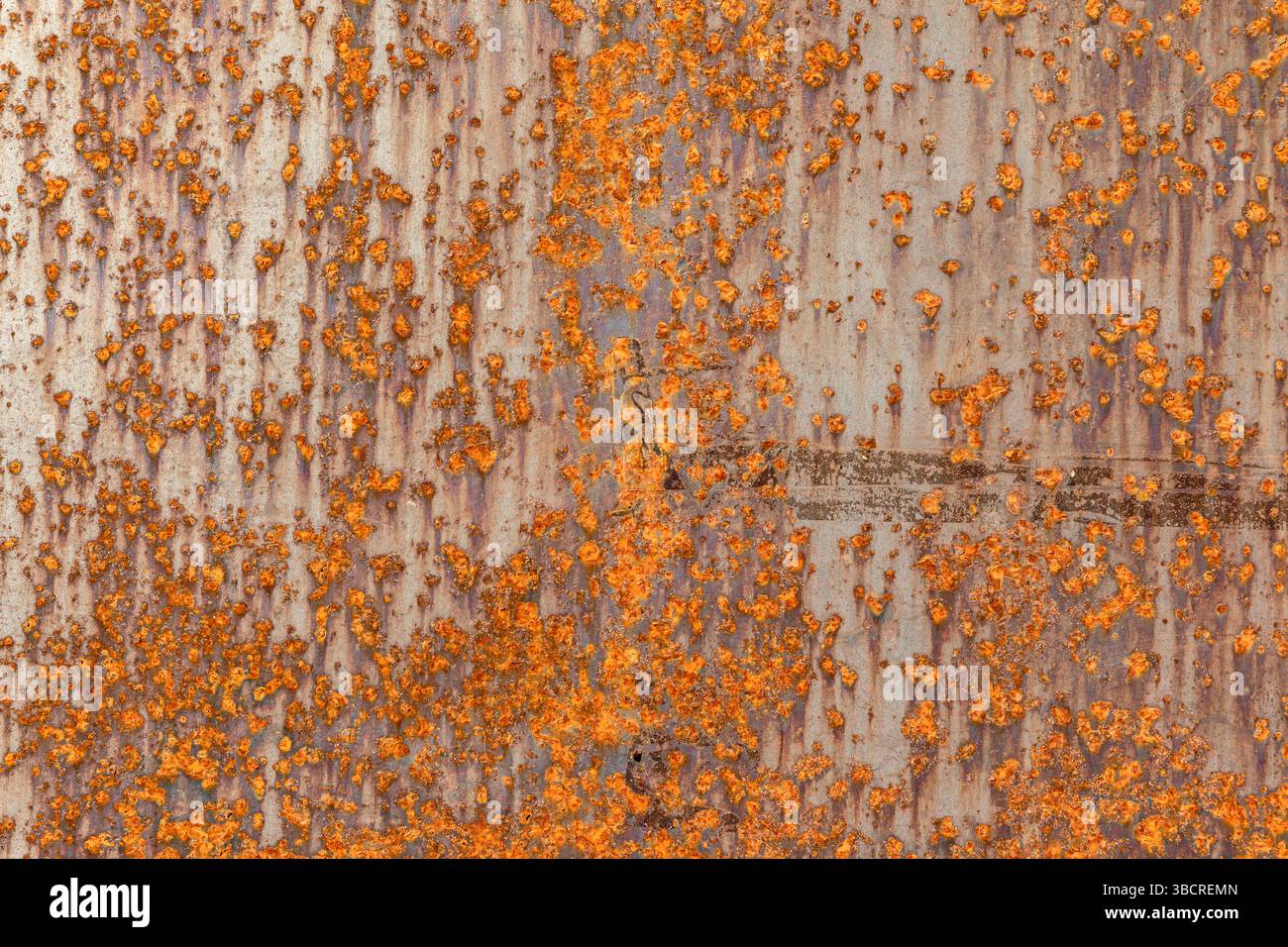 Primo piano di una superficie in metallo corroso ricoperta di ruggine arancione, che mostra il decadimento industriale e la consistenza grintosa per sfondi o per l'uso nel design. Foto Stock