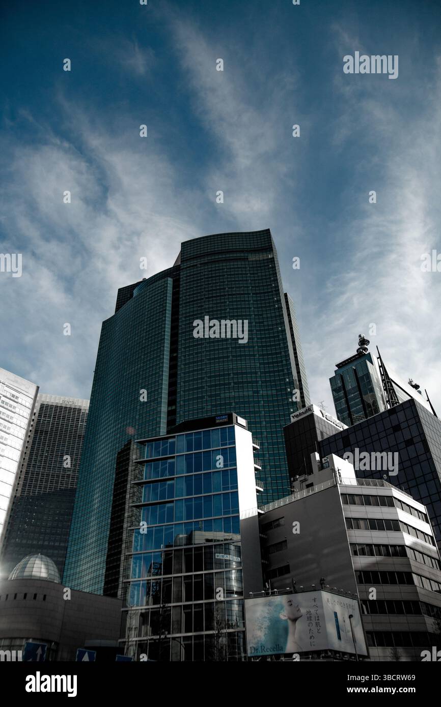 Un gruppo di moderni grattacieli sotto un cielo nuvoloso nel centro di Tokyo, in Giappone, che mostrano densità e consistenza urbana Foto Stock