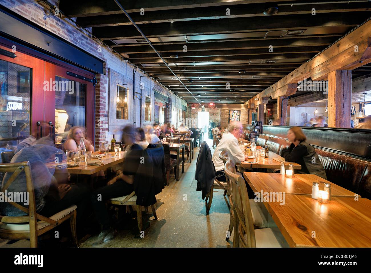 Virtue Feed and Grain Restaurant Interior Alexandria Virginia // ALEXANDRIA, Virginia - il ristorante Virtue Feed and Grain occupa un magazzino storico nel cuore della città vecchia di Alexandria. L'edificio, originariamente costruito negli anni '1800 come negozio di alimenti e cereali, è stato meticolosamente restaurato e convertito in un popolare ristorante. Situato vicino al lungomare del fiume Potomac, il ristorante presenta pareti in mattoni a vista, travi in legno e decorazioni di ispirazione industriale che rendono omaggio al suo passato utilitaristico. Foto Stock