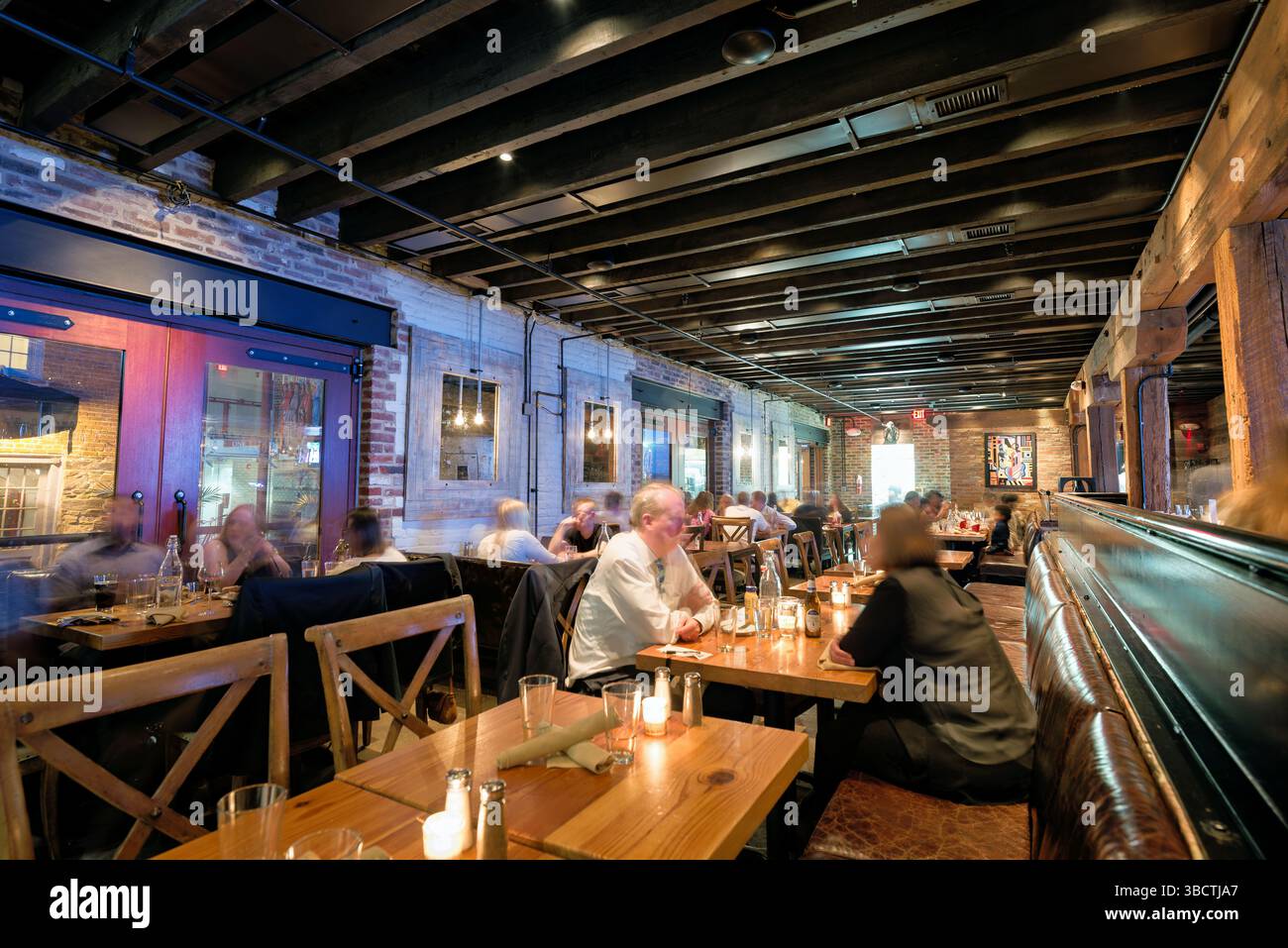 Virtue Feed and Grain Restaurant Interior Alexandria Virginia // ALEXANDRIA, Virginia - il ristorante Virtue Feed and Grain occupa un magazzino storico nel cuore della città vecchia di Alexandria. L'edificio, originariamente costruito negli anni '1800 come negozio di alimenti e cereali, è stato meticolosamente restaurato e convertito in un popolare ristorante. Situato vicino al lungomare del fiume Potomac, il ristorante presenta pareti in mattoni a vista, travi in legno e decorazioni di ispirazione industriale che rendono omaggio al suo passato utilitaristico. Foto Stock