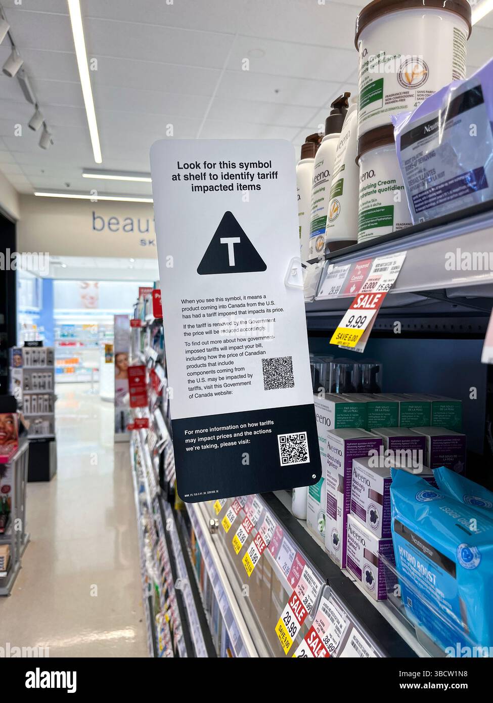 East Gwillimbury, Ontario, Canada - 20 maggio 2025: Un cartello su uno scaffale del negozio Shoppers Drug Mart che spiega il simbolo T per quanto riguarda la tariffa interessata Foto Stock