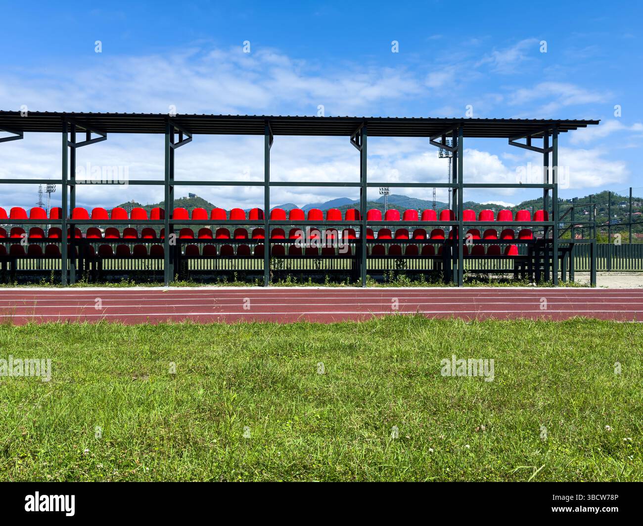 Stadio all'aperto con posti a sedere in plastica rossa, pista e campo, nessuno. Infrastrutture per impianti sportivi, solo per uso editoriale. Foto Stock