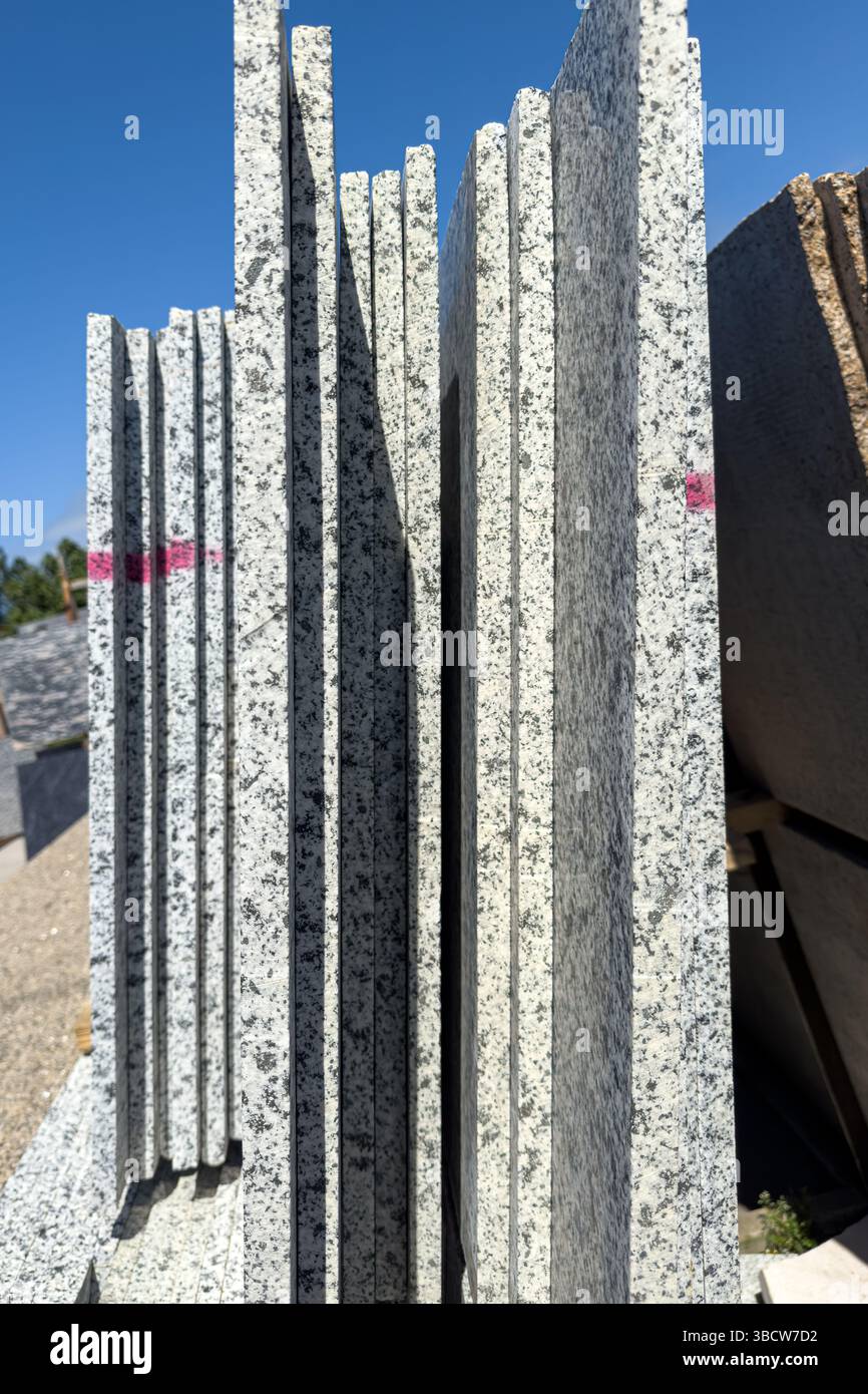 Lastre di granito disposte verticalmente all'esterno, che mostrano la consistenza industriale e i segni della sega. Solo per uso editoriale, niente persone. Foto Stock