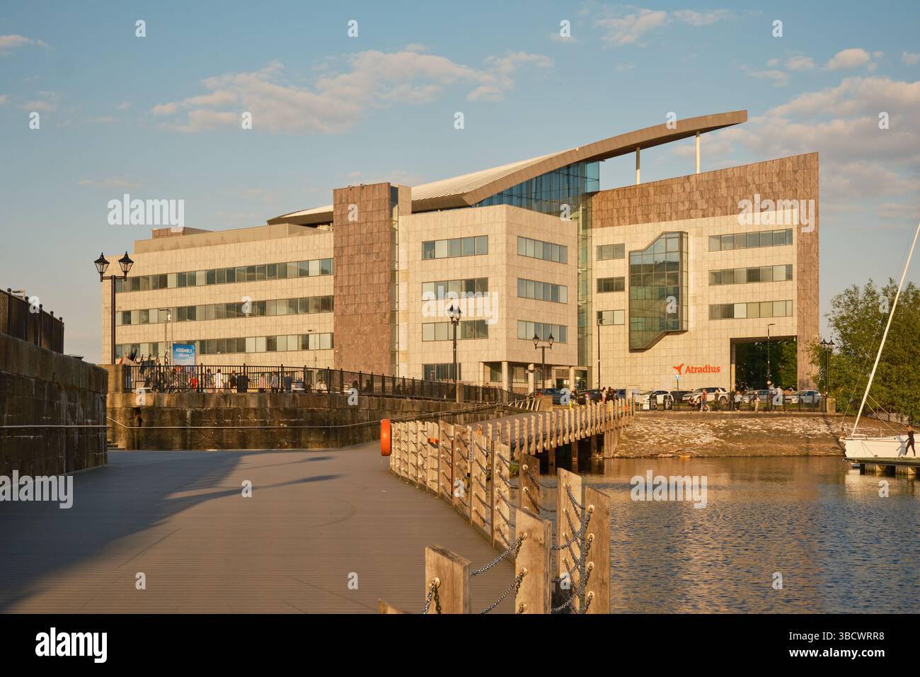 Moderno edificio per uffici Atradius a Cardiff Bay, Galles del Sud, fotografato all'ora d'oro con lungomare, passerella e porticciolo visibili in primo piano. Foto Stock