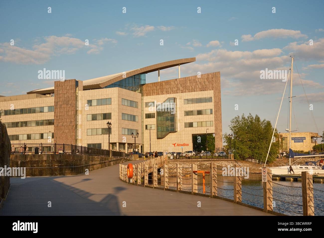 Moderno edificio per uffici Atradius a Cardiff Bay, Galles del Sud, fotografato all'ora d'oro con lungomare, passerella e porticciolo visibili in primo piano. Foto Stock
