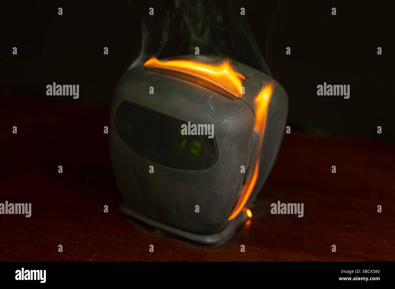 Un orologio o un ricevitore radio incandescenti, con il fumo che sale verso l'alto. La scena mostra il pericolo che i vecchi componenti elettronici si incendiino Foto Stock