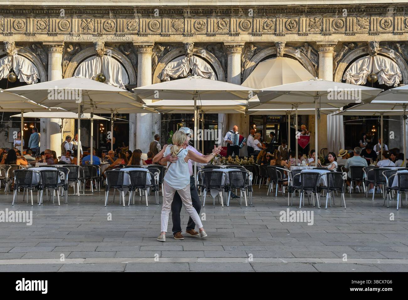 Un paio di turisti di mezza età che ballano di fronte allo storico caffè Florian in Piazza San Marco, Venezia, Veneto, Italia Foto Stock