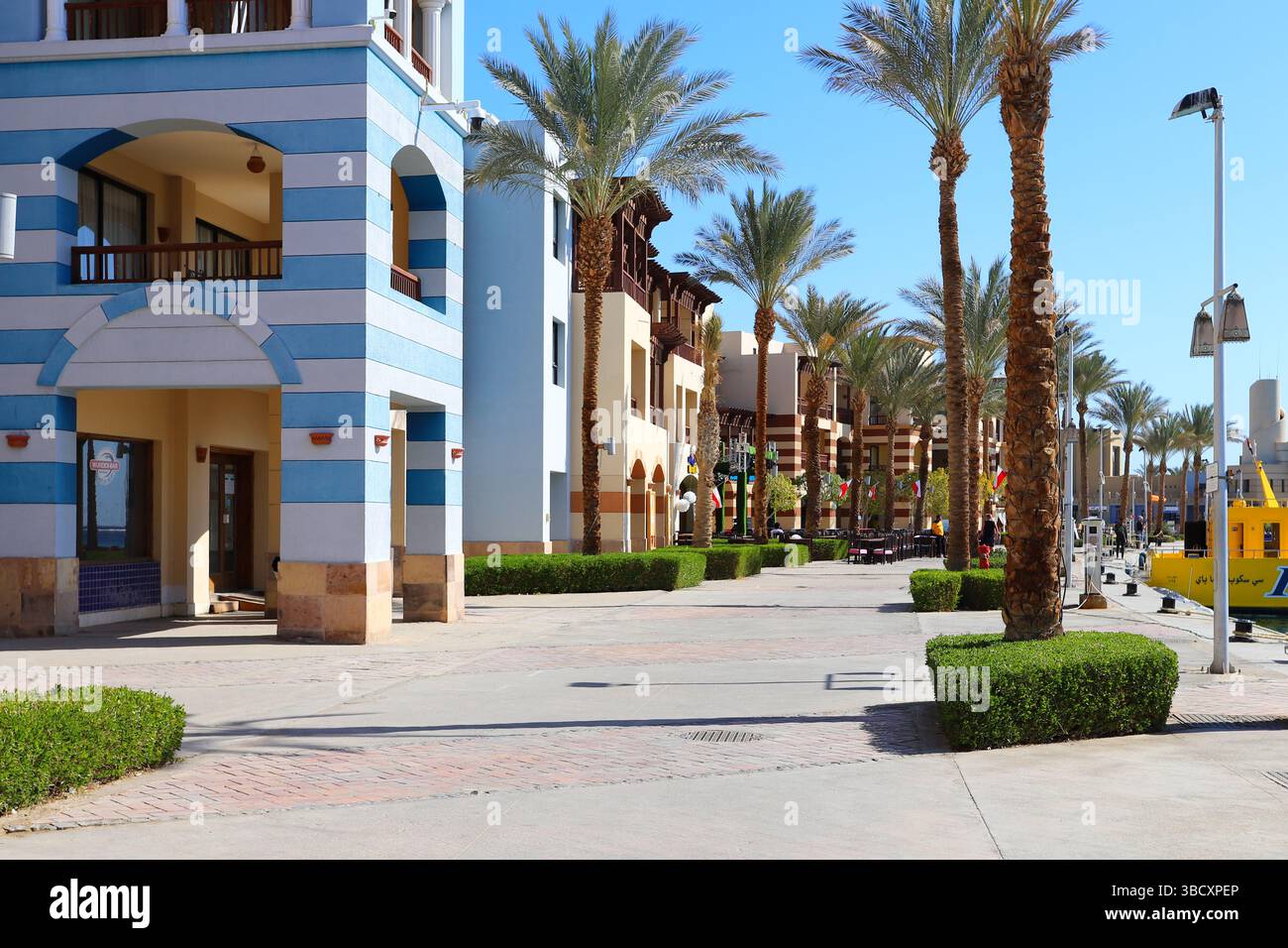Il colorato lungomare del Mar Rosso con palme, edifici a righe in stile mediterraneo e un'atmosfera tranquilla sotto il cielo blu. Foto Stock
