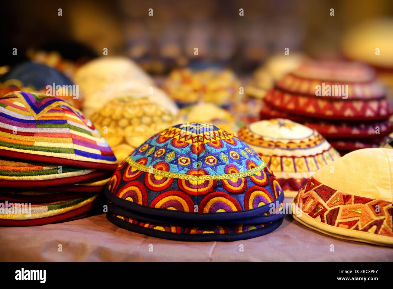Colorate kippah ricamate (yarmulke) esposte in una bancarella del mercato mediorientale, che mostrano l'intricata artigianato tessile tradizionale. Foto Stock