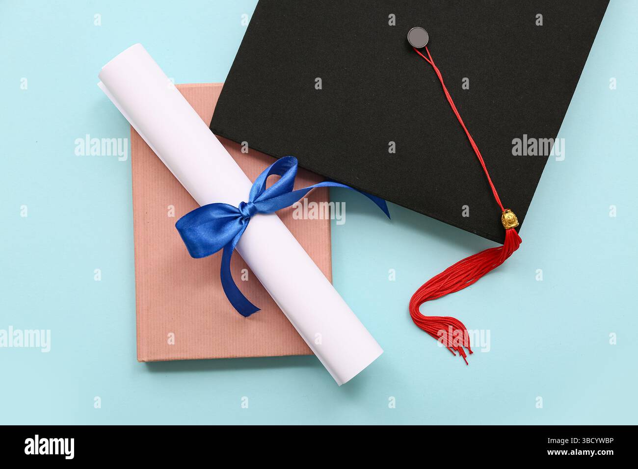 Diploma con nastro blu, libro e cappello graduato su sfondo azzurro Foto Stock