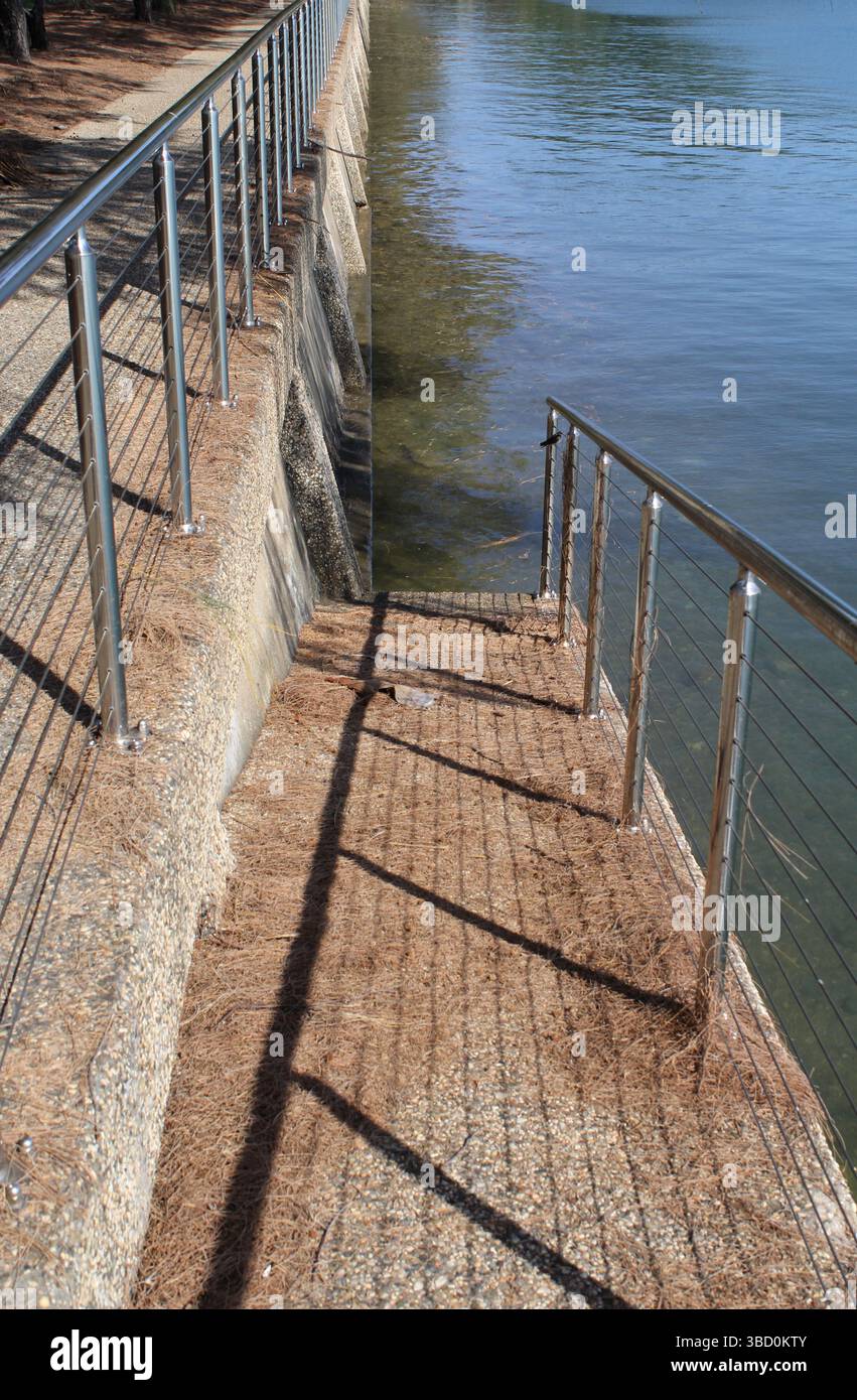 Rampa di cemento con una recinzione che conduce all'acqua marina dell'oceano Foto Stock