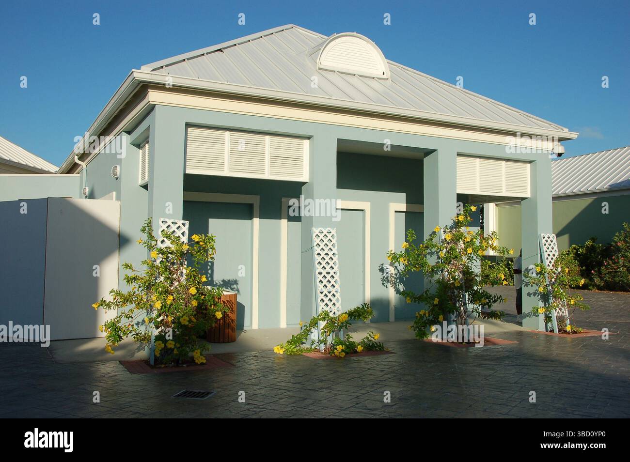 Colorati edifici in stile coloniale e un cortile paesaggistico con palme e una fontana presso il porto crocieristico di Grand Turk, Turks e Caicos Foto Stock