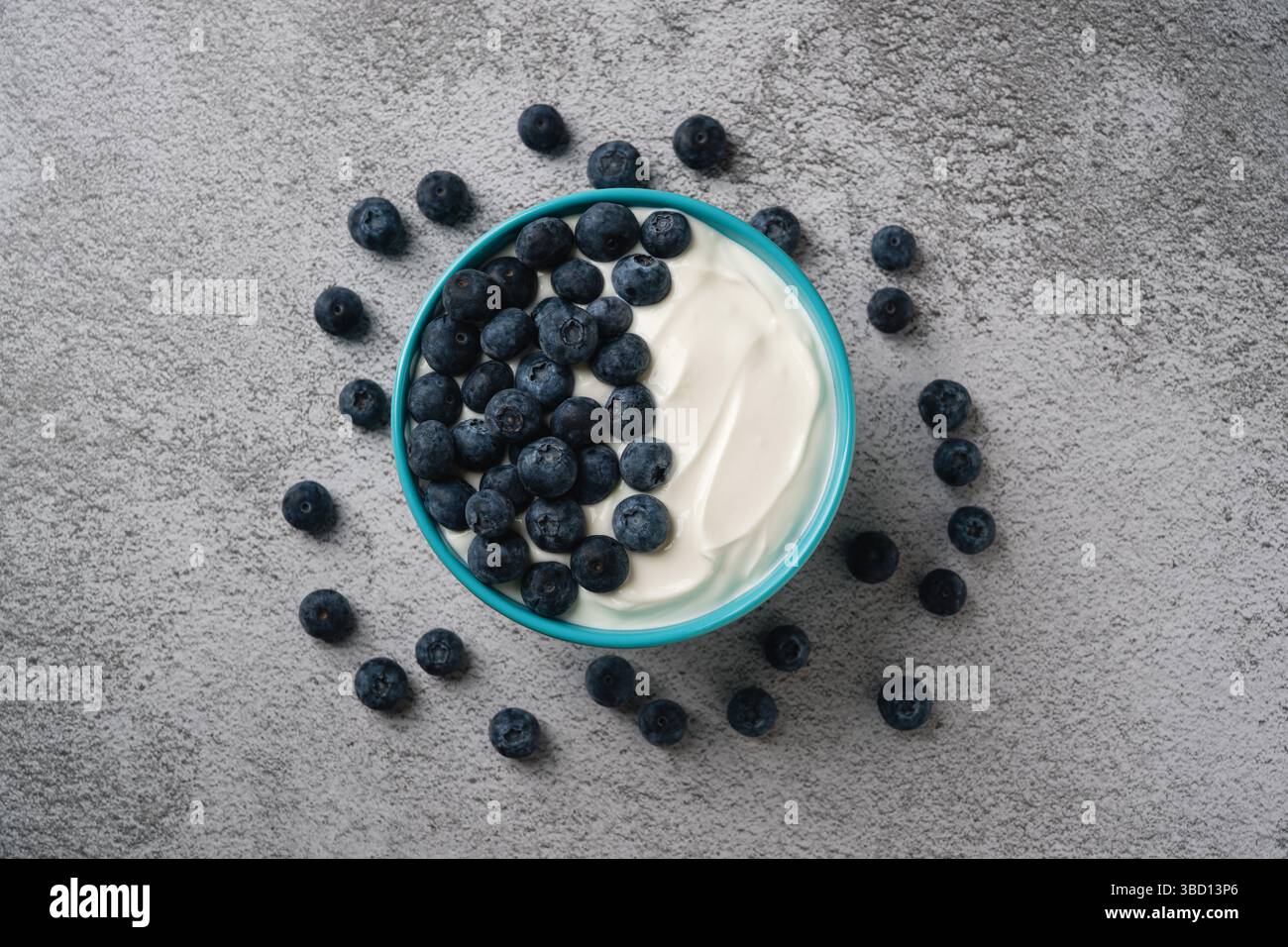 Vista dall'alto dei mirtilli freschi su uno yogurt cremoso in una ciotola blu Foto Stock