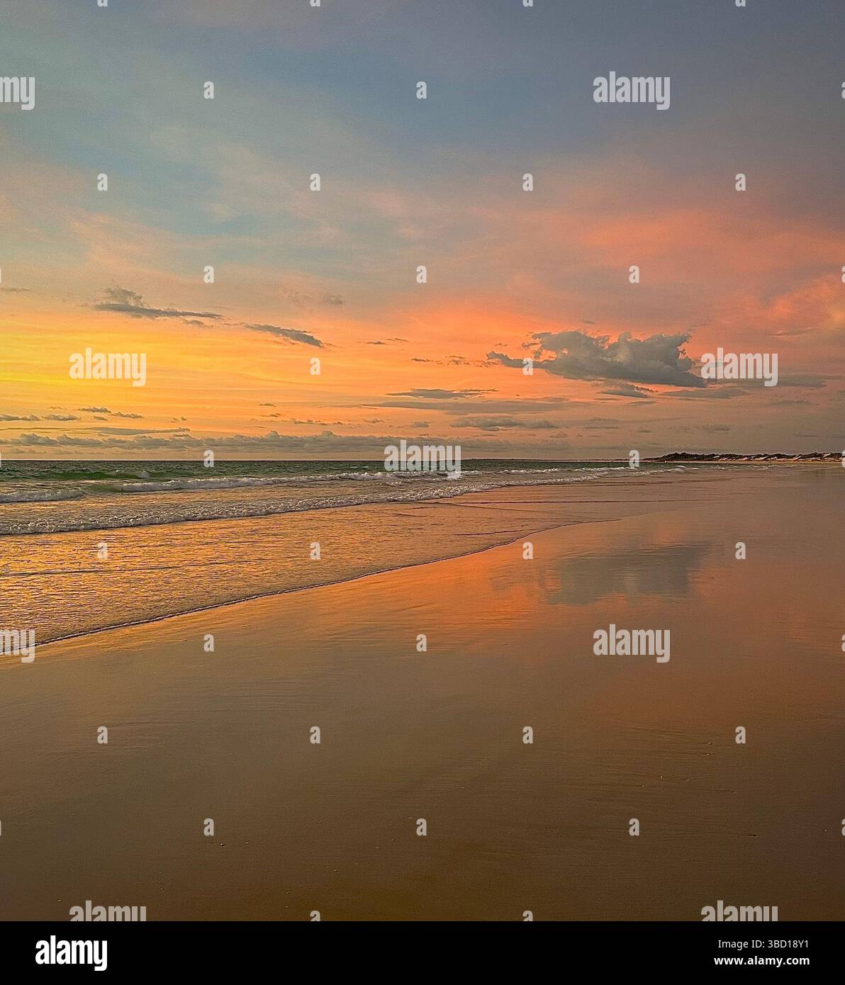 Soffice tramonto color pastello su una spiaggia tranquilla con onde dolci e riflessi dorati sulla sabbia bagnata: Una tranquilla scena costiera perfetta per viaggi e benessere. - Immagine stock catturata con smartphone