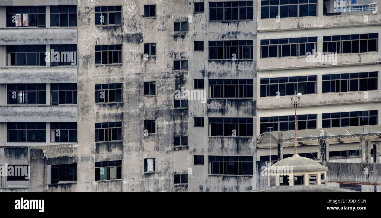 Un edificio abbandonato intempestivo con macchie scure, pareti incrinate e finestre rotte. Questa struttura urbana in decomposizione riflette l'abbandono, il decadimento e l'hau Foto Stock