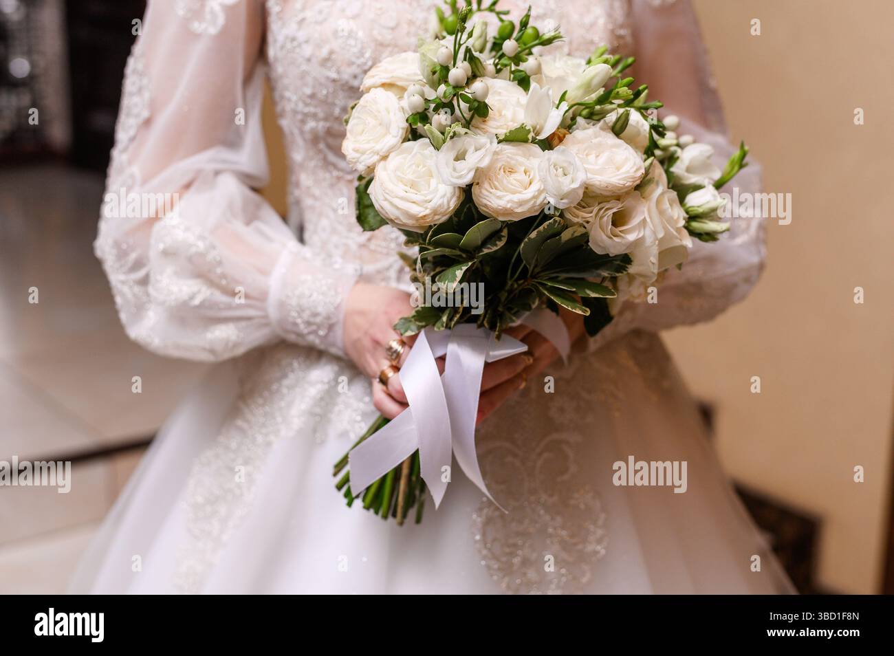 L'abito da sposa bianco regala un fresco bouquet floreale. Primo piano delle mani della sposa che reggono un bouquet delicato splendide rose bianche, petali bianchi matchi Foto Stock