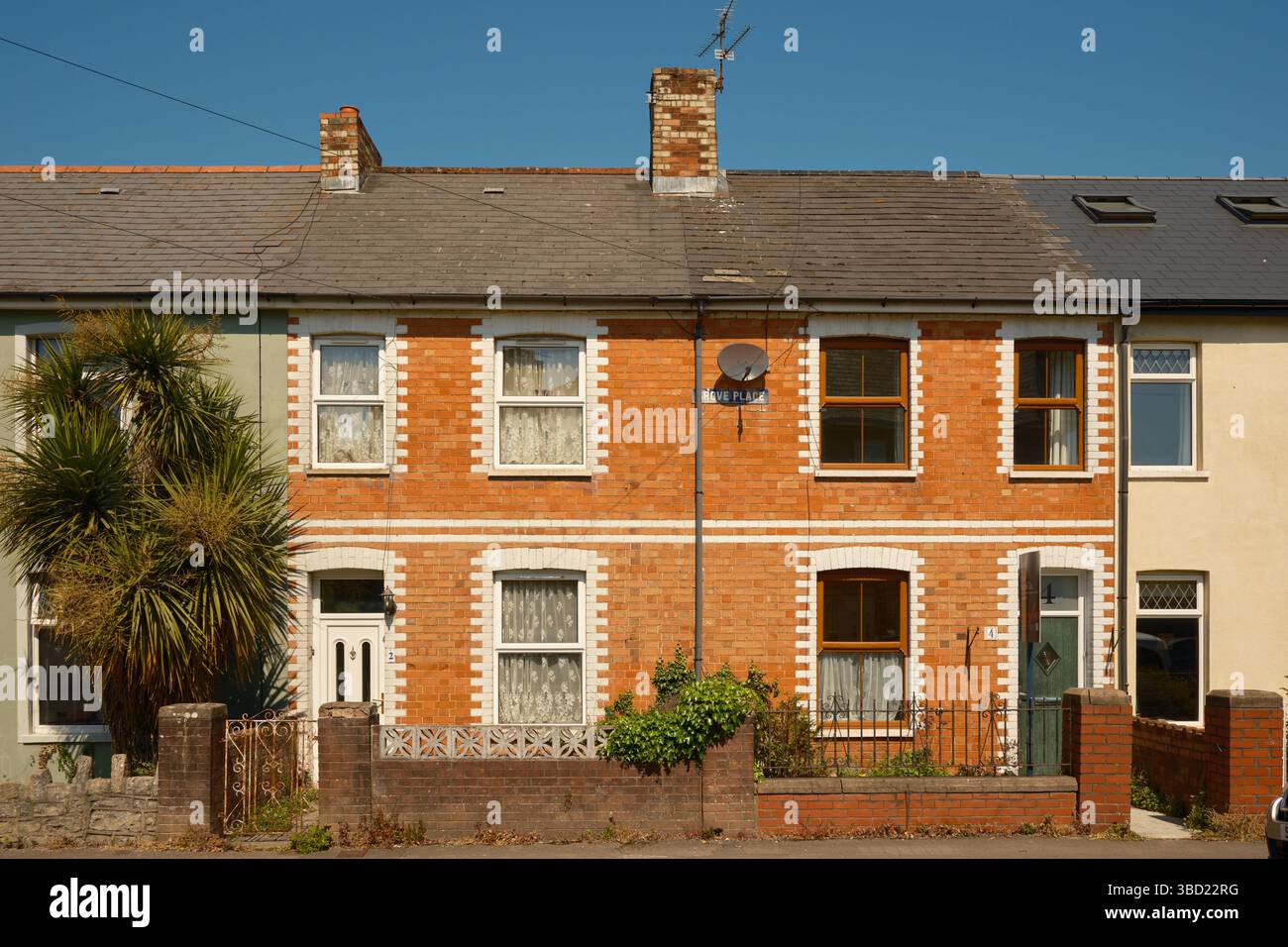 Tradizionali case terrazzate in mattoni rossi con finiture in pietra bianca a Penarth, Galles del Sud, in una giornata di sole con cielo azzurro e piccoli giardini frontali. Foto Stock