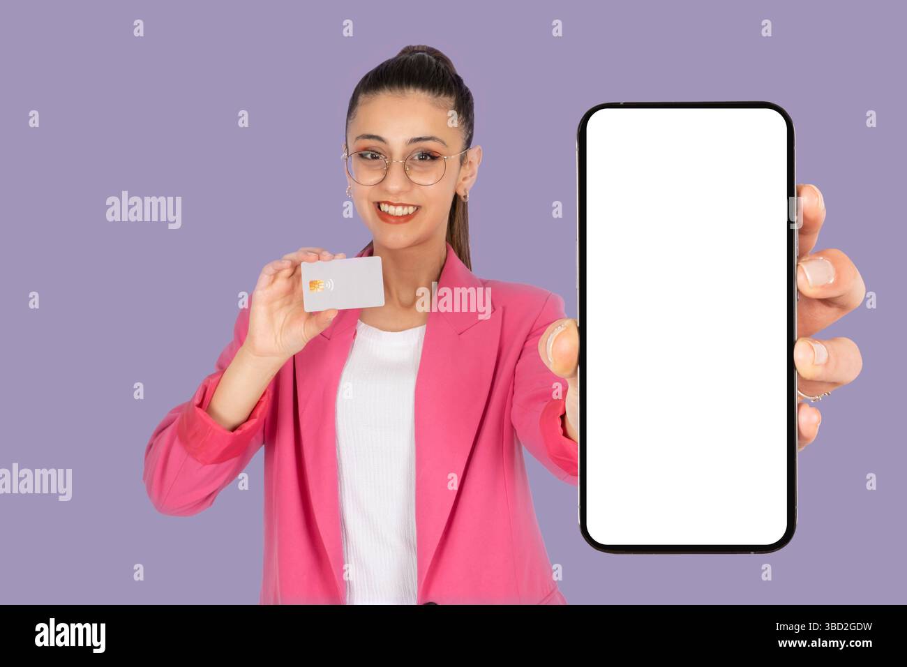 donna con carta di credito bancaria e con un modello di cellulare bianco vuoto. Offerta mobile isolata con sfondo viola pastello. Foto Stock