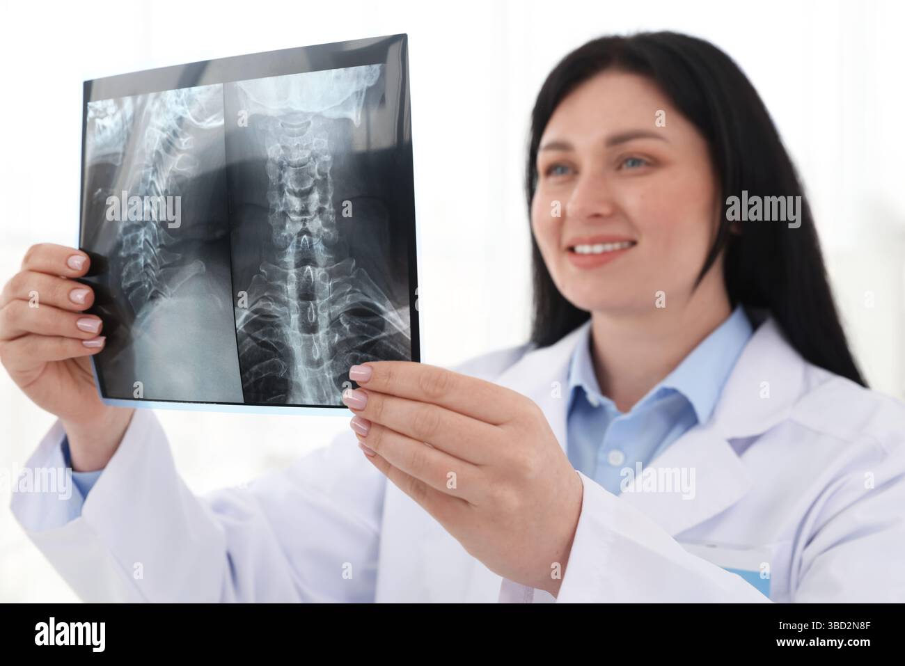 Medico sorridente che esamina la scansione RM del collo in clinica Foto Stock
