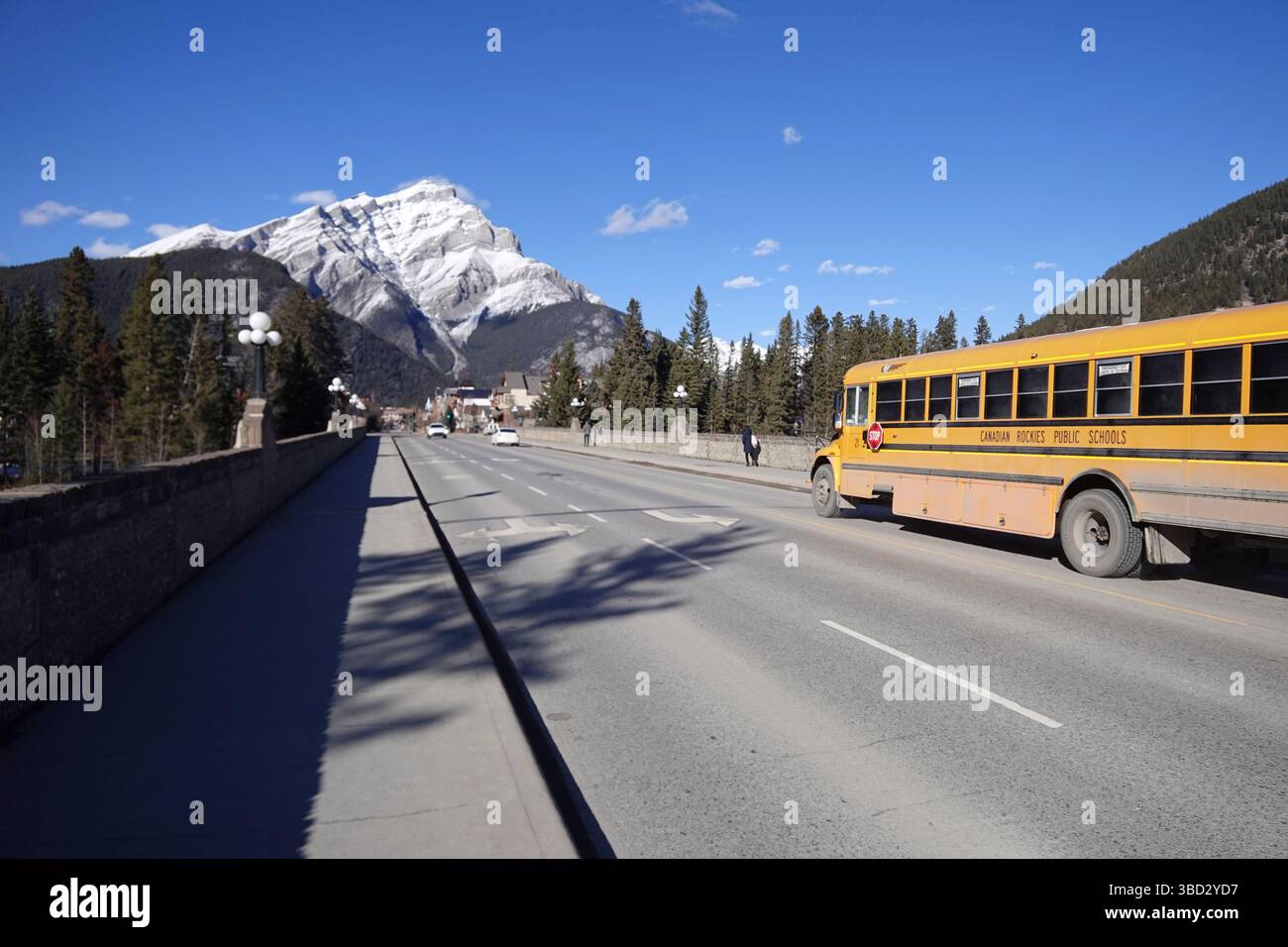 Banff Avenue guarda verso Cascade Mountain con lo scuolabus giallo Foto Stock