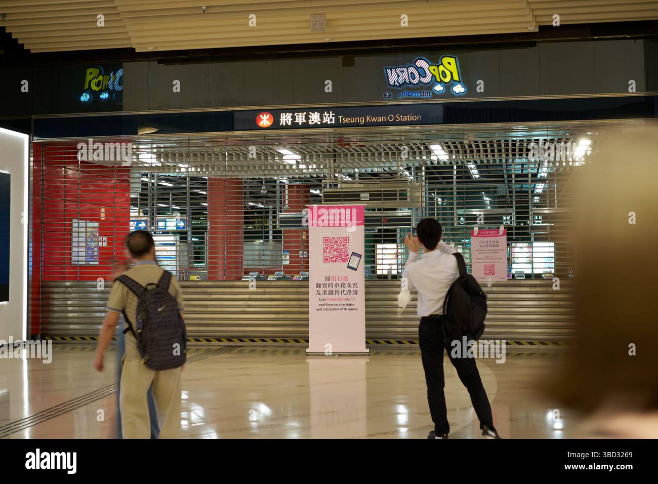 I passeggeri che scansionano il codice QR sul cartello posto dalla MTR come servizio ferroviario per la linea Tseung Kwan o sono stati sospesi dopo un'interruzione dell'alimentazione elettrica. Foto Stock
