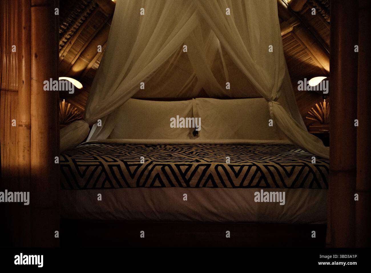 Tranquillo rifugio in bambù con tende bianche a baldacchino all'interno di una capanna di bambù Foto Stock