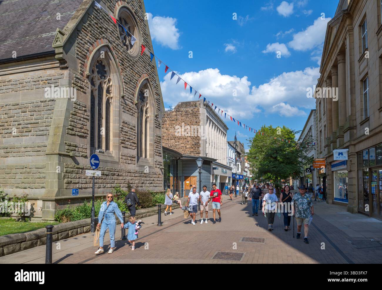 Negozi su Cambridge Street nel centro della città con la chiesa di San Pietro a sinistra, Harrogate, North Yorkshire, Inghilterra, Regno Unito Foto Stock
