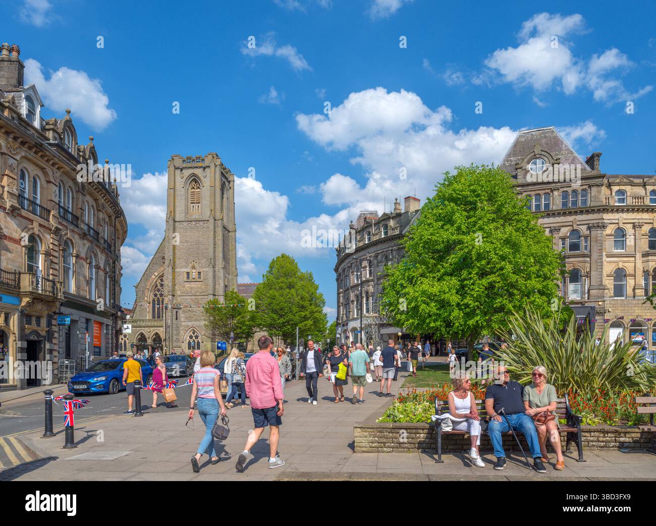 Negozi su Cambridge Crescent nel centro della città con la chiesa di San Pietro a sinistra, Harrogate, North Yorkshire, Inghilterra, Regno Unito Foto Stock