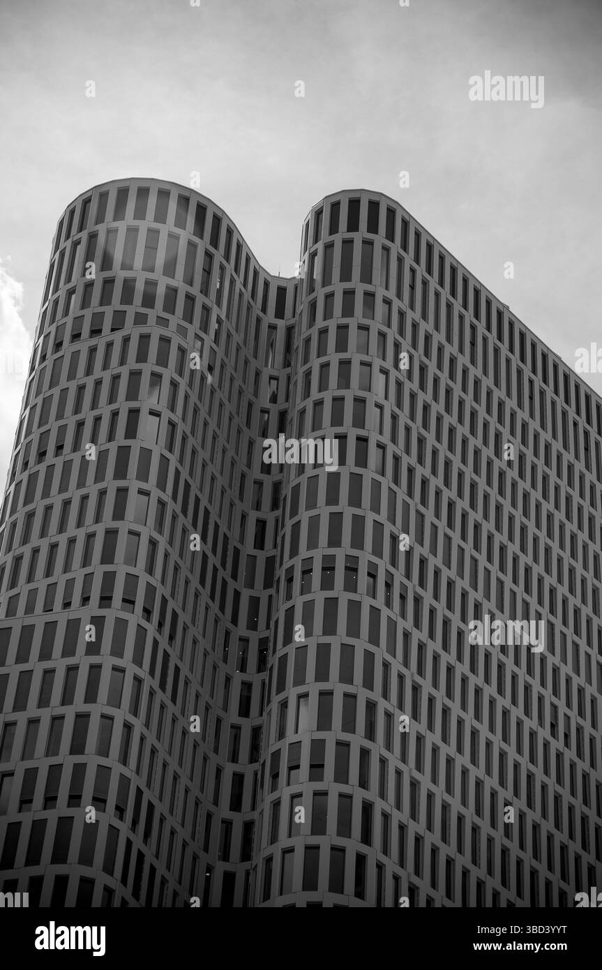 L'edificio unico di Berlino presenta un'architettura contemporanea con i suoi bordi curvi e la facciata suggestiva, adagiata su un cielo mooso. Foto Stock