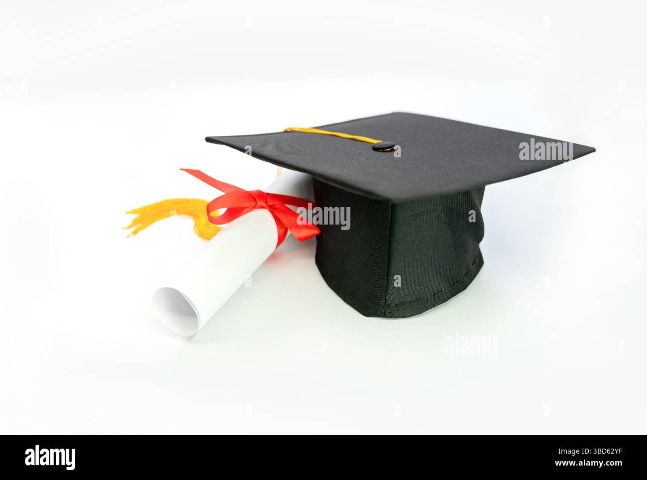 Un cappello di graduazione e un rotolo di diploma posizionati su uno sfondo bianco. Finite l'istruzione. Foto Stock
