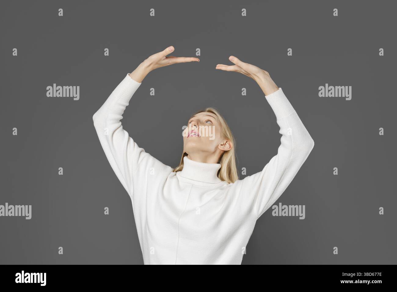 Una giovane donna alzò entrambe le mani, palma in alto, come se fosse appoggiata su un soffitto invisibile Foto Stock